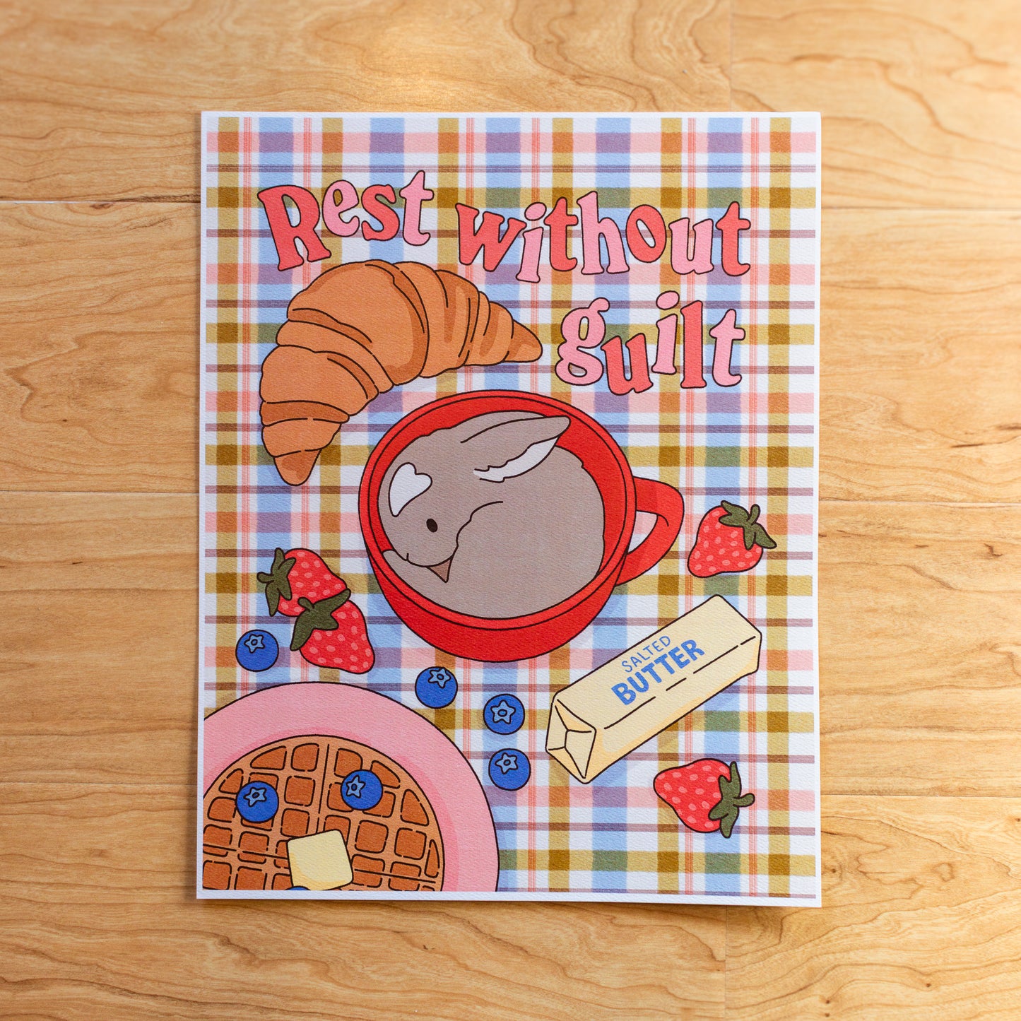 Art print with breakfast-themed illustration and 'Rest without Guilt' text on a plaid background