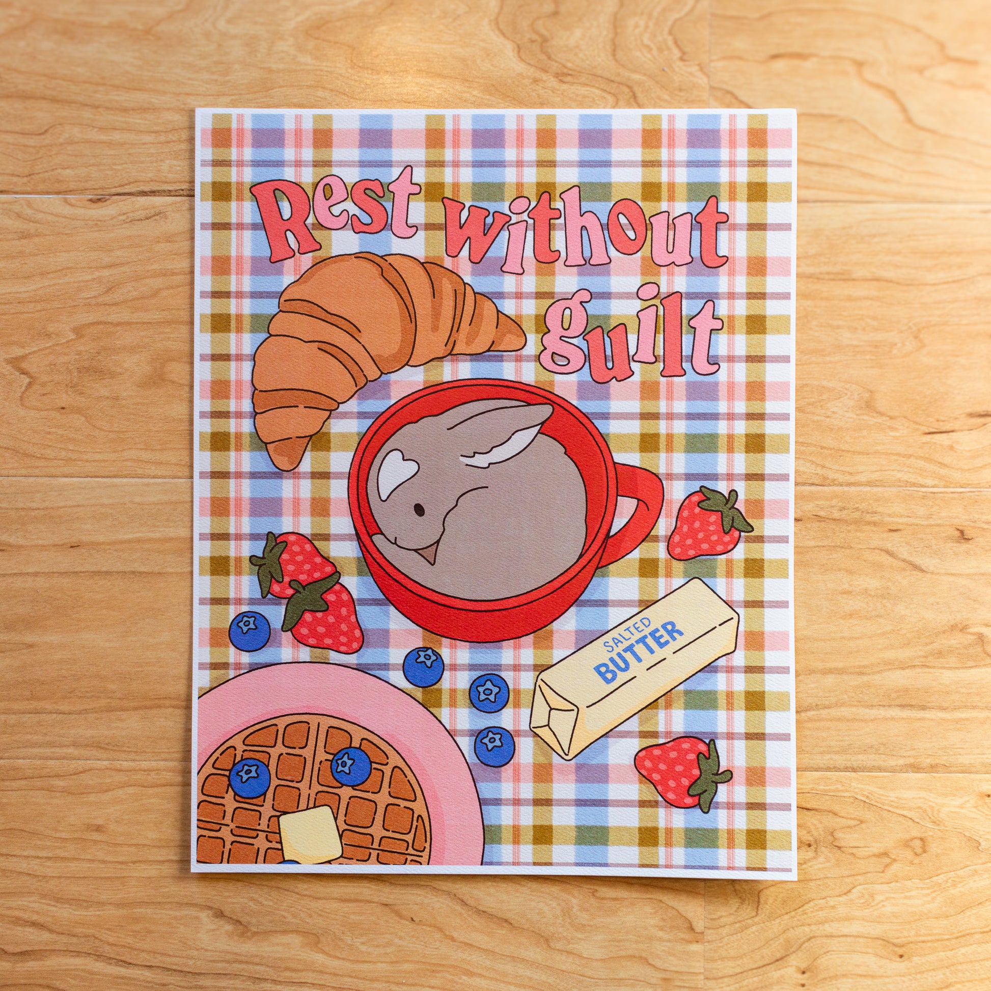 Art print with breakfast-themed illustration and 'Rest without Guilt' text on a plaid background